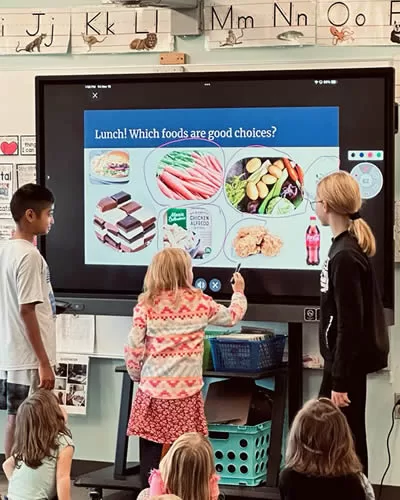 Students teaching peers healthy eating habits with a Tower Garden.